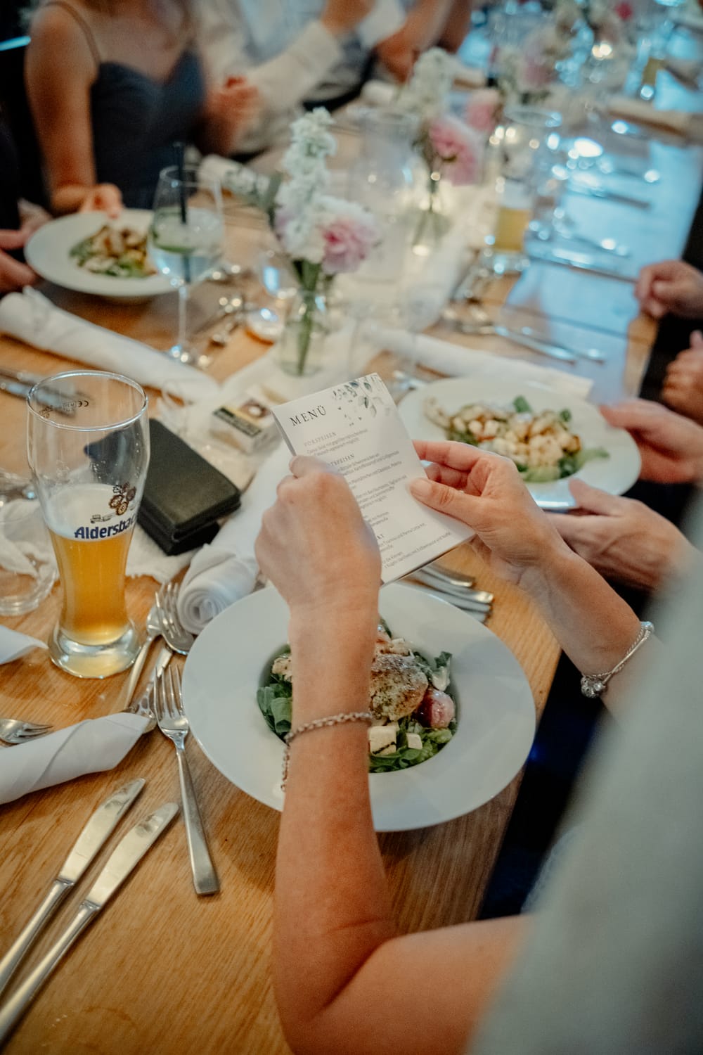 Hochzeitsgäste beim Dinner, eine Gästin liest die Menükarte