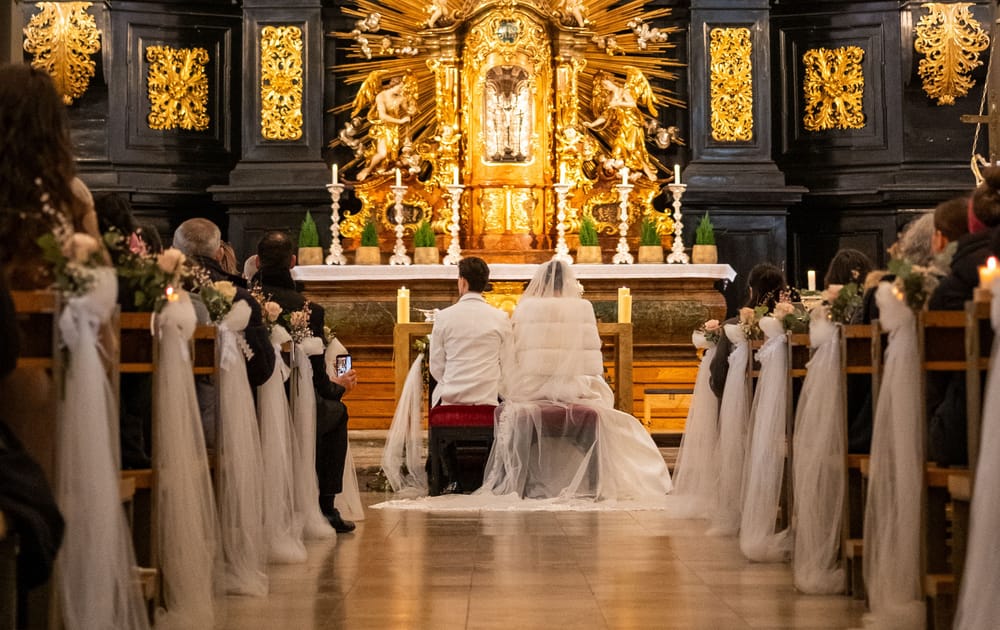 Brautpaar sitzt vor barockem Altar während der kirchlichen Trauung