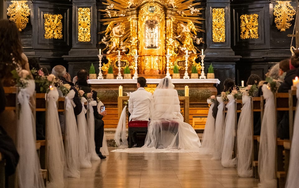 Brautpaar sitzt vor barockem Altar während der kirchlichen Trauung
