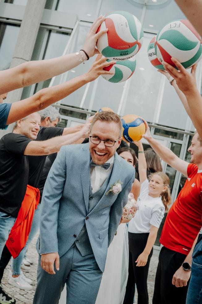 Bräutigam läuft durch Spalier aus Volleybällen